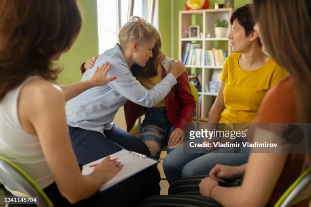 a woman embracing a young girl sitting next to her to show her empathy - story telling in the workplace stockfoto's en -beelden