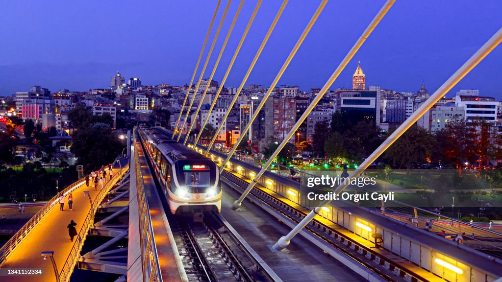 The Golden Horn Metro Bridge and Istanbul cityscape with lights at sunset