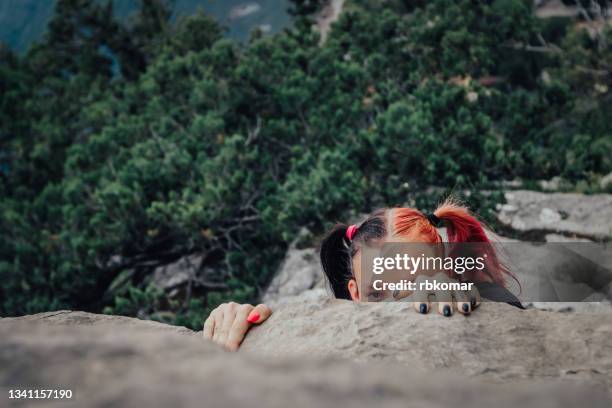 young rock climber gripping to a rock - überhängend stock-fotos und bilder