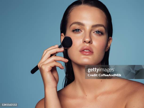 beautiful young woman applying foundation powder - make up blush imagens e fotografias de stock