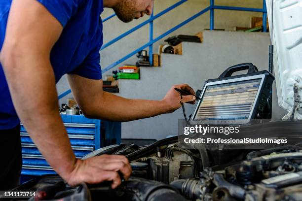 a car mechanic is analyzing and checking the condition of the car with computer. - mecânico imagens e fotografias de stock