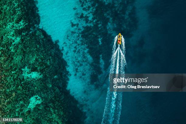 aerial drone view of tourist diving boat on turquoise color ocean water surface with coral reef - speedboat foto e immagini stock