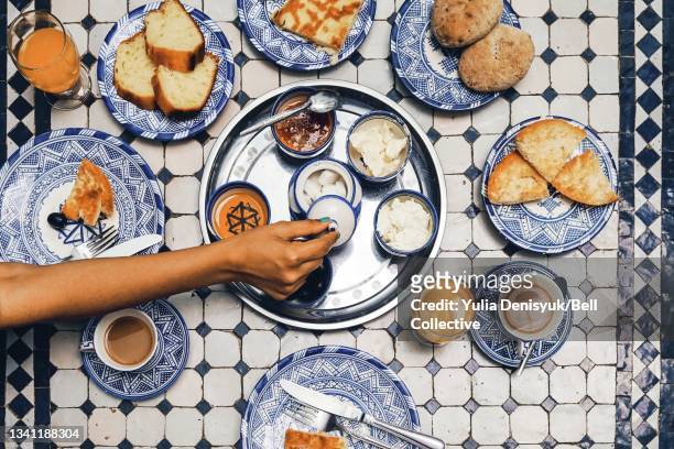 A woman is opening up a jar with sugar at a breakfast in a Moroccan riad