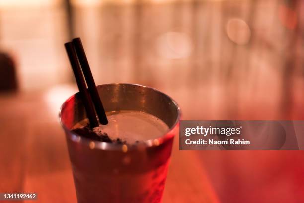 milkshake in a retro-style stainless steel malt cup, with a red bokeh illuminated background - ステンレス ストックフォトと画像