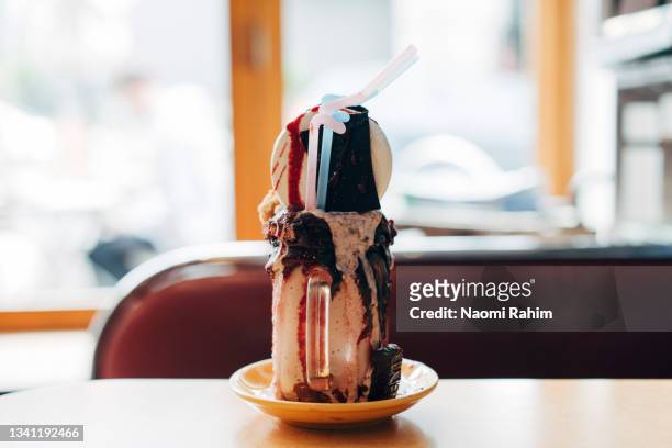 decadent mega milkshake topped with cream and chocolate, served in a vintage mason jar - overflowing glass stock-fotos und bilder