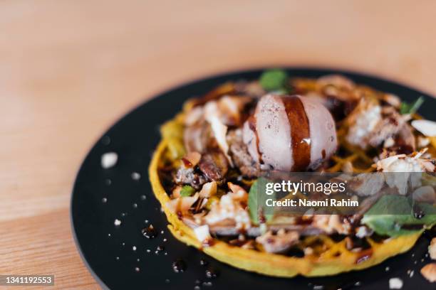 tumeric waffles, topped with icecream, vegan dessert, served on a black plate - savoury food stock-fotos und bilder