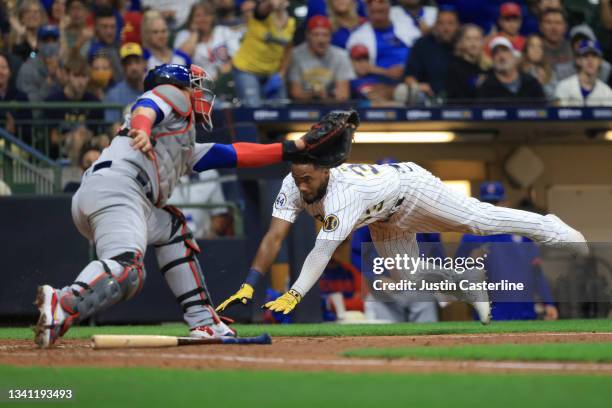 Pablo Reyes of the Milwaukee Brewers slides into home while Willson Contreras of the Chicago Cubs attempts to make the out during the eighth inning...