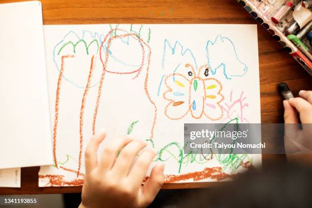 a boy draws a picture with crayons on drawing paper - kid holding crayons stockfoto's en -beelden