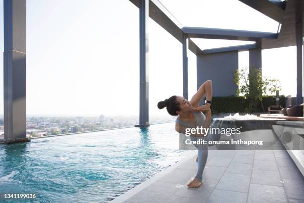 extractive asia woman praktiziert yoga neben pool auf dem excusive dach der eigentumswohnung, urban health lifestyle - athlete training urban gym stock-fotos und bilder