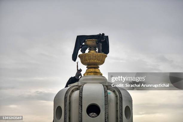 Protesters drape a banner over the Democracy Monument during a "car mob rally" on September 19, 2021 in Bangkok, Thailand. Anti-government protesters...