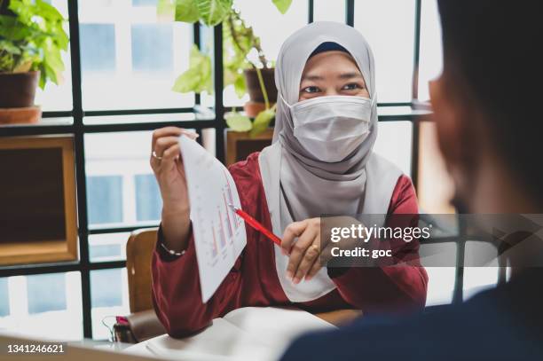 muslim businesswoman with hijab meeting and brainstorming, having discussion on business strategy with her colleague in co-working office - business meeting with masks stock pictures, royalty-free photos & images