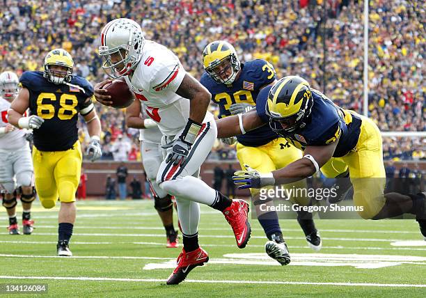 Braxton Miller of the Ohio State Buckeyes gets in for a second quarter touchdown past Kenny Demens of the Michigan Wolverines at Michigan Stadium on...