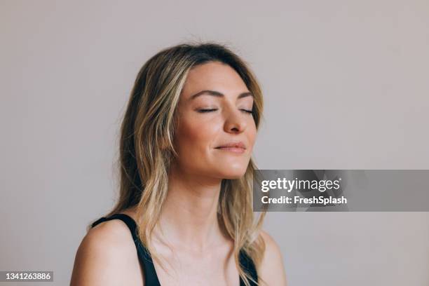 horizontal close up shot of a beautiful blonde woman meditating with her eyes closed - eyes closed stockfoto's en -beelden