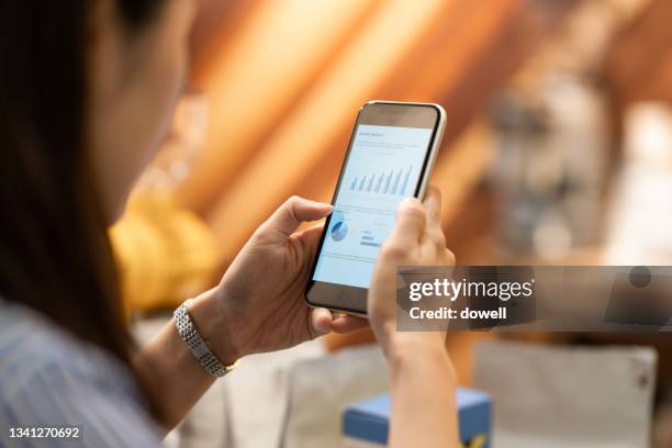 closeup shot of a businesswoman analyzing statistics on a smart phone - smart numbers office stockfoto's en -beelden