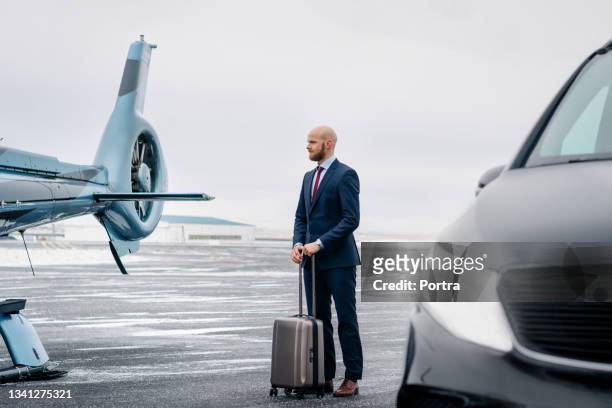businessman with his bag standing on airstrip by a chopper - helicopter stock pictures, royalty-free photos & images