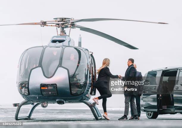 wealthy couple traveling by a private helicopter - helikopter stockfoto's en -beelden