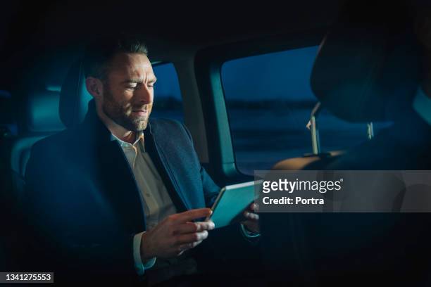 車で仕事に旅行中にタブレットコンピュータで働くビジネスマン - high society ストックフォトと画像