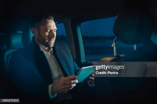 businessman working on tablet computer while traveling to work in car - high society imagens e fotografias de stock