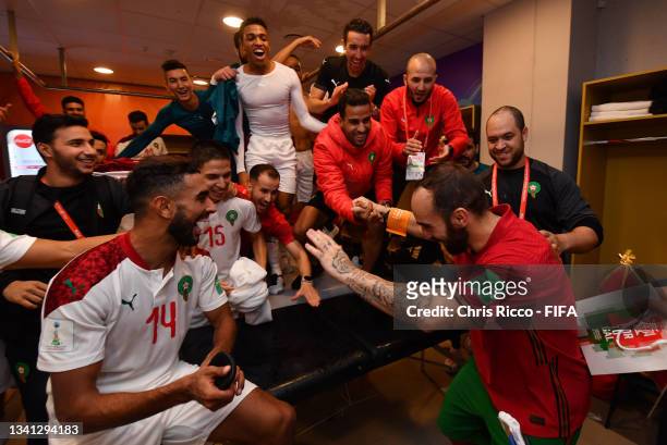 Players of Morocco celebrate in the dressing room after qualifying for the knockout stages as they are congratulated by Ricardinho of Portugal...