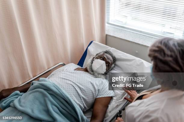 doctor talking to patient on hospital ward - wearing protective face mask - covid funeral stock pictures, royalty-free photos & images