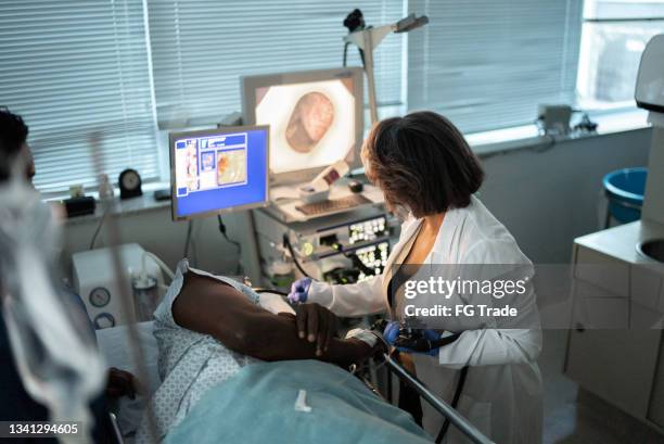 mature doctor doing an endoscopy exam in patient - endoscope stock pictures, royalty-free photos & images