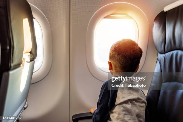 junge im flugzeug mit blick aus dem fenster - safe kids day arrivals stock-fotos und bilder