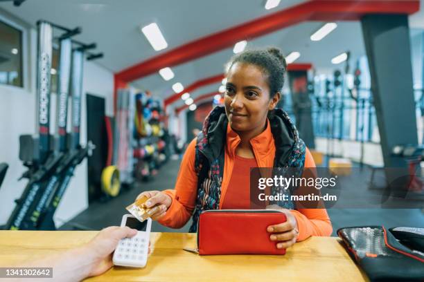 frau im fitnessstudio zahlt kontaktlos - charging sports stock-fotos und bilder