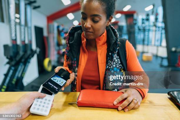 woman in the gym paying with smart phone - lady wallet stock pictures, royalty-free photos & images