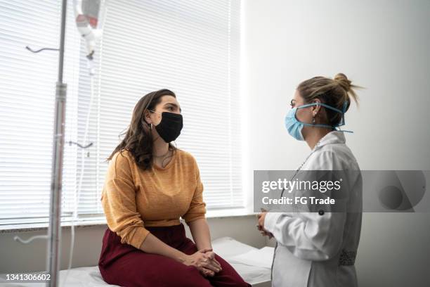 patient talking to doctor on medical appointment - wearing protective face mask - masker stockfoto's en -beelden