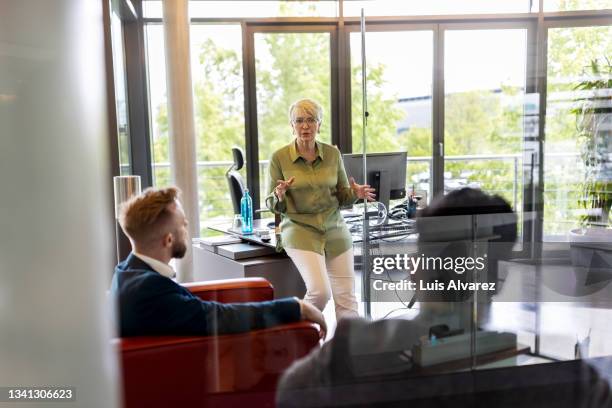 ceo having meeting with two male colleagues in her office - gerentes ejecutivos fotografías e imágenes de stock