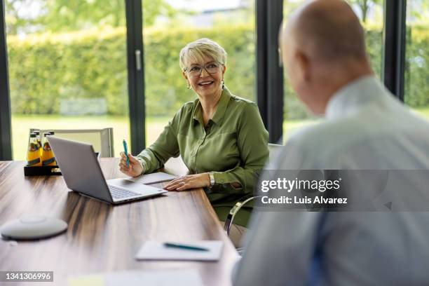 businesswoman discussing new plans with partner in meeting - green shirt stock pictures, royalty-free photos & images