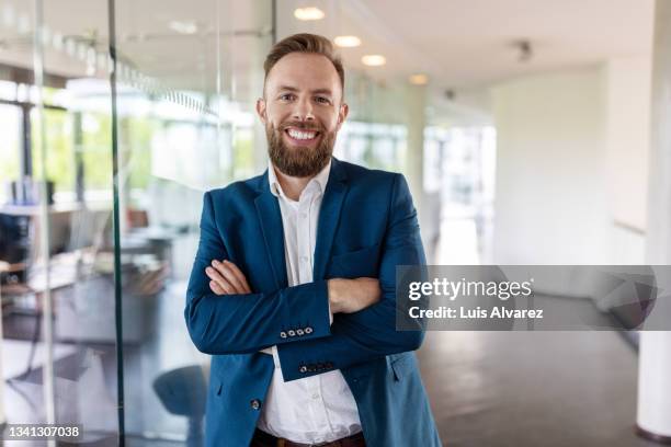 portrait of a confident businessman standing in office - costume bleu photos et images de collection