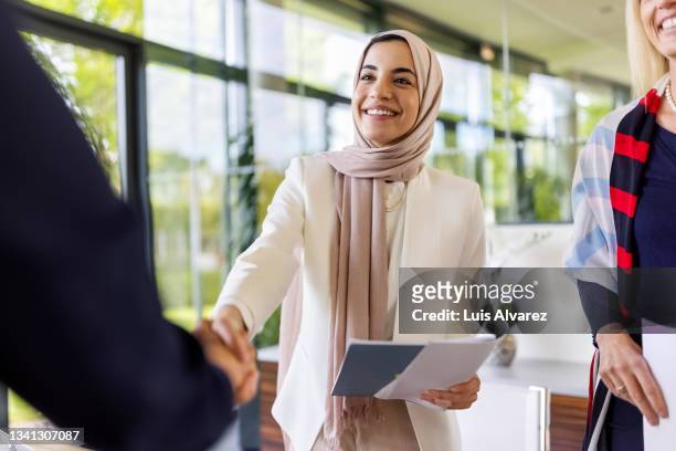 muslim businesswomen sealing a deal with a handshake - islam stock-fotos und bilder