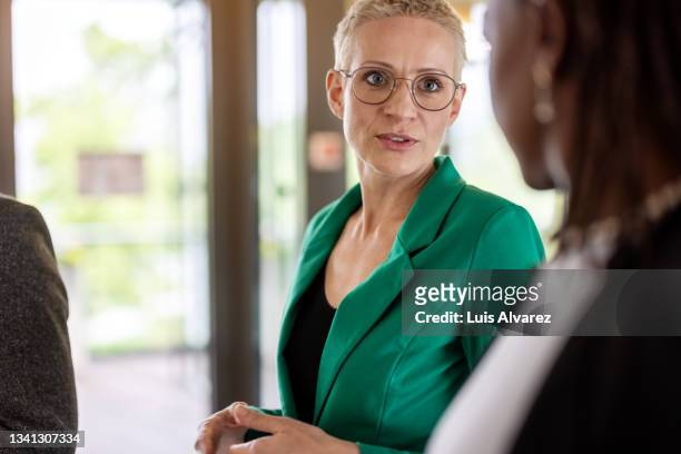female entrepreneur talking with a business partner in the office - green blazer stockfoto's en -beelden