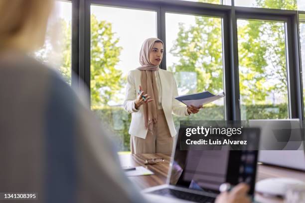 business woman with headscarf with file briefing project details in meeting - islamismo fotografías e imágenes de stock