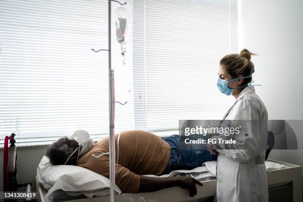 patient lying on hospital ward during exam on medical appointment - wearing protective face mask - gastroenteritis stock pictures, royalty-free photos & images