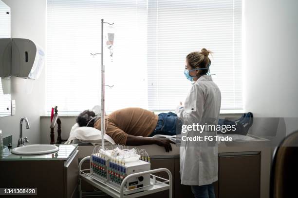 patient lying on hospital ward during exam on medical appointment - wearing protective face mask - african american funeral stock pictures, royalty-free photos & images