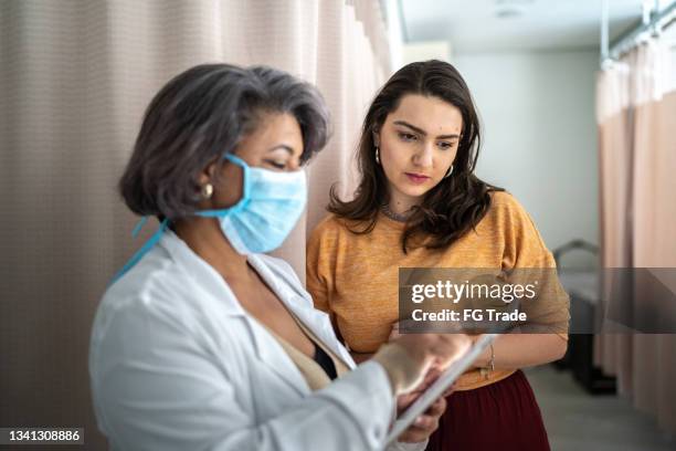 doctor talking to patient during medical appointment in a hospital - wearing protective face mask - hispanic medical exam stock pictures, royalty-free photos & images