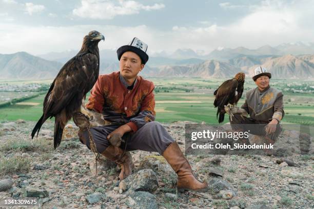 two eagle hunters in steppe in kyrgyzstan - kyrgyzstan stock pictures, royalty-free photos & images