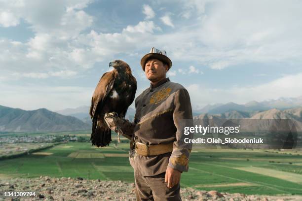 cazador de águilas de pie en el fondo de las montañas en kirguistán - cetrería fotografías e imágenes de stock