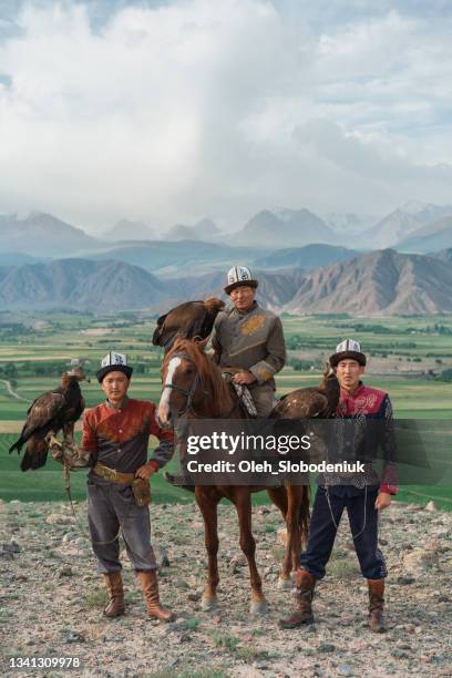 three eagle hunters  in steppe in kyrgyzstan - kyrgyzstan people stock pictures, royalty-free photos & images