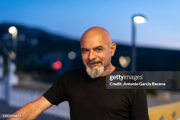 mature 60-year-old man is portrayed at nightfall during blue hour with traffic lights in the background - porträtt man ansikte bakgrundsoskärpa bildbanksfoton och bilder