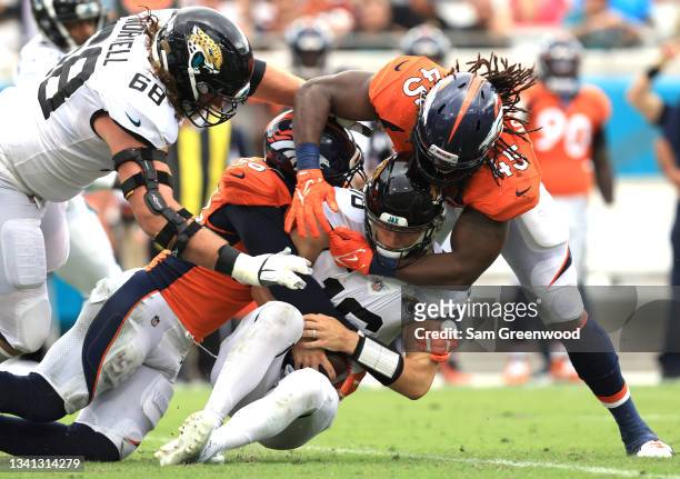 Linebacker Von Miller and linebacker Alexander Johnson of the Denver Broncos tackle quarterback Trevor Lawrence of the Jacksonville Jaguars during...