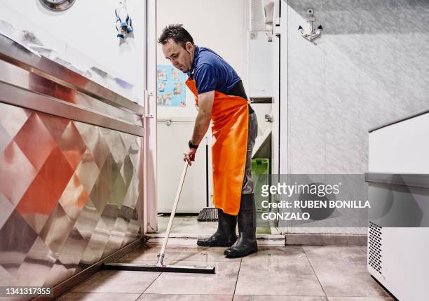 caucasian worker at seafood market cleaning and sweeping the store floor using a broom. small business and food concept - gonzalo caballero fotografías e imágenes de stock