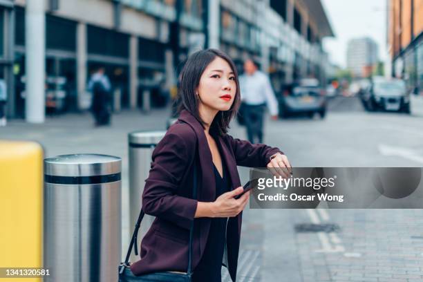 asian businesswoman holding smart phone, waiting for taxi in the city during rush hour - taxi worried bildbanksfoton och bilder