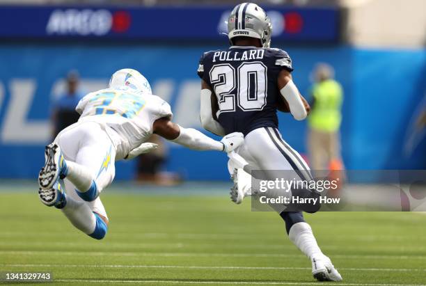 Running back Tony Pollard of the Dallas Cowboys runs from a tackle by free safety Derwin James of the Los Angeles Chargers during the first quarter...