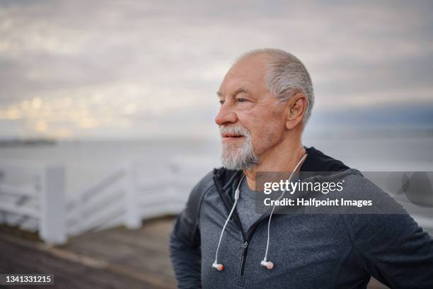 portrait of active senior man resting after doing exercise outdoors on pier by sea in early morning. - daily life in poland stock-fotos und bilder