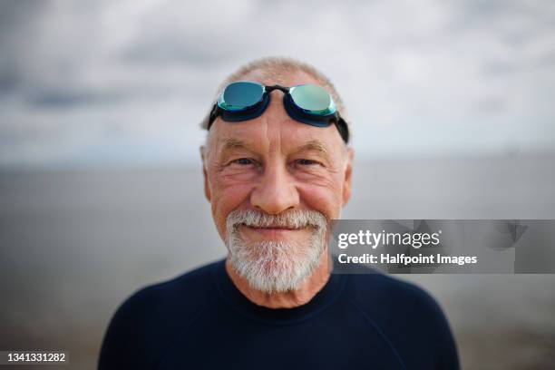 portrait of happy actvie senior swimmer after early morning swim in sea, looking at camera. - adult swim imagens e fotografias de stock
