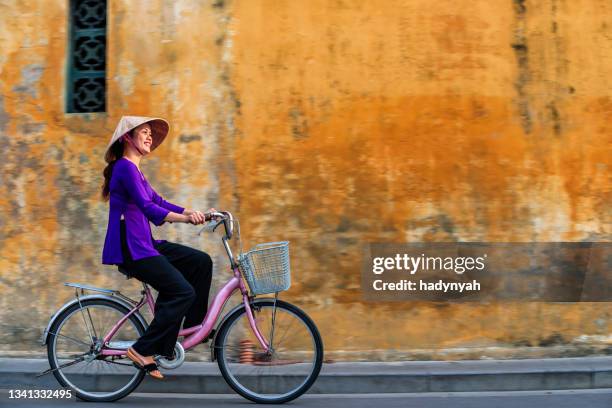 vietnamese woman riding a bicycle, old town in hoi an city, vietnam - vietnam wall stock pictures, royalty-free photos & images