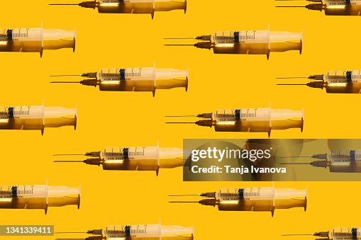 Pattern of syringes with a vaccine on yellow background. Concept of medical treatment or vaccination. Pattern of syringes with a vaccine on yellow background. Concept of medical treatment or vaccination.